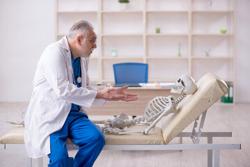 Old male doctor and skeleton patient in the clinic