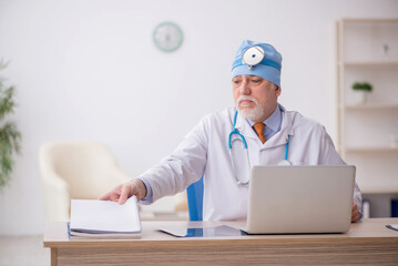 Old male doctor otologist working in the clinic