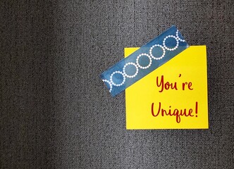 Note stick on wallpaper background with handwritten text You're Unique, concept of positive...