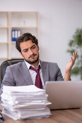 Naklejka premium Young male employee and too much work in the office