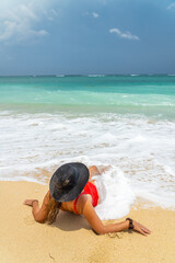 Fototapeta na wymiar Woman with reb swimsuit and black hat at the beach in Bali indonesia