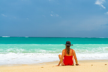 Obraz premium Woman with reb swimsuit and black hat at the beach in Bali indonesia