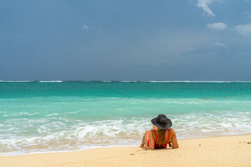 Woman with reb swimsuit and black hat at the beach in Bali indonesia