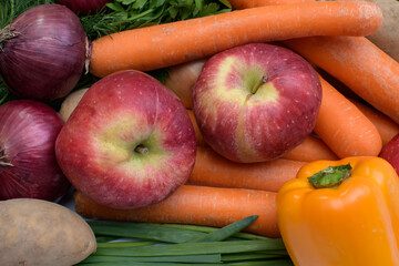 Papryka, jabłka i marchew makro na tle zielonych ziół 