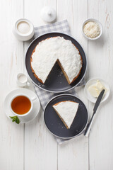 Boston bun is a big, spiced bun with thick layer of coconut icing on the exterior, while the interior contains mashed potatoes and raisins closeup on the table. Vertical top view from above