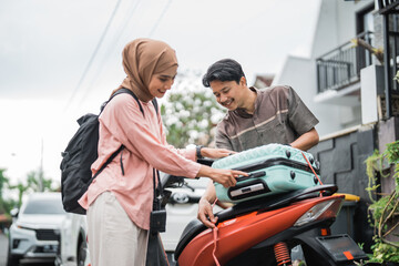 Fototapeta na wymiar happy asian muslim couple pack his suitcase on motorbike travel during eid mubarak back to hometown