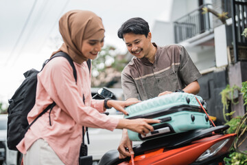 Fototapeta na wymiar happy asian muslim couple pack his suitcase on motorbike travel during eid mubarak back to hometown