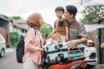 asian muslim family riding motorbike scooter together traveling with kid. eid mubarak travel concept
