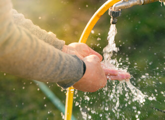 Washing hands from garden tap with cold water in morning