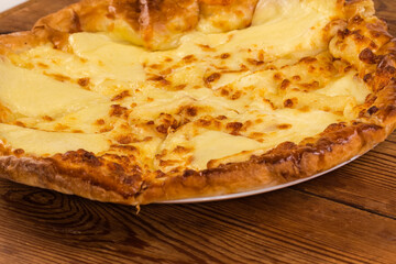 Baked khachapuri on dish on rustic table, close-up