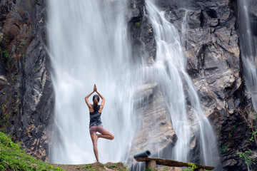 Asian traveller woman pose yoga in lotus pose with waterfall background