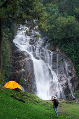 woman traveller walk togather Tent and camping with Mae Tia waterfall and mountain background at inthanon national park in Chiang mai