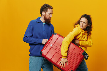 Obraz premium Woman and man smiling, suitcases in hand with yellow and red suitcase smiling merrily and crooked, yellow background, going on a trip, family vacation trip, newlyweds.