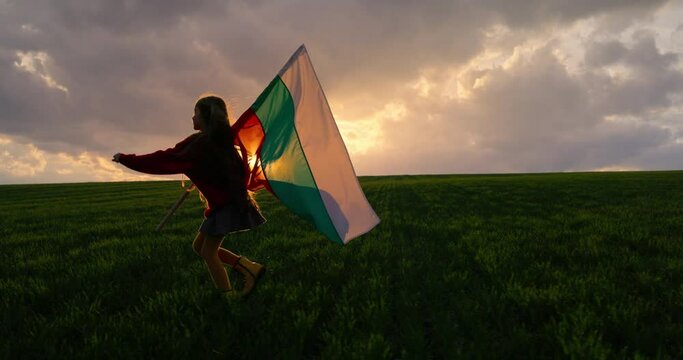 Young patriotic girl with bulgarian flag running on green wheat field at sunset in countryside, Bulgaria 4k video