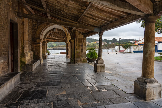 Passageway with arched doors and wooden roof with old stone columns in the church of Luanco, Asturias.