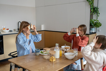 Joyful caucasian family young mother and two kids having fun during breakfast at home, bonding and enjoying morning time together at home. Mom enjoy early hours with children before school