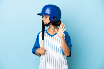 Baseball mixed race player woman with helmet and bat isolated on blue background making stop gesture and disappointed