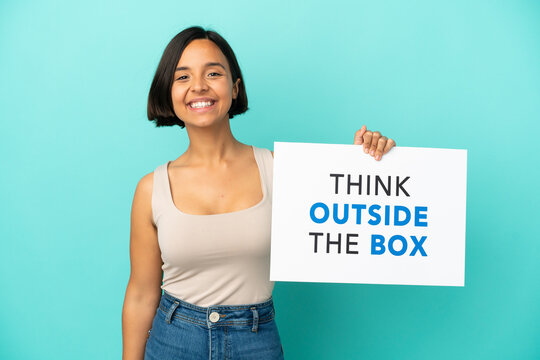 Young mixed race woman isolated on blue background holding a placard with text Think Outside The Box with happy expression