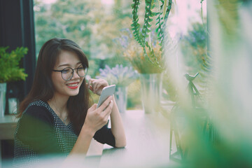beautiful asian younger woman reading message in smart phone and smiling with happiness face