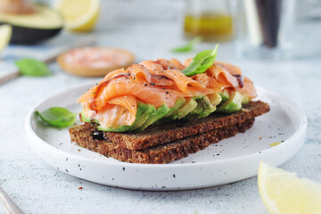 A rye bread sandwich with avocado and salmon	