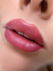 permanent makeup on the lips of a young woman of a delicate peach shade close-up - obrazy, fototapety, plakaty