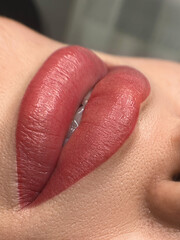 permanent makeup on the lips of a young woman of a delicate peach shade close-up