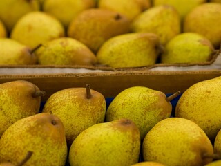 Closeup shot of yellow pears placed inside of a box seen in the market