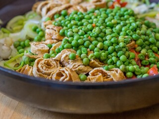 Closeup shot of a bowl filled with noodles and vegetables like peas and onions