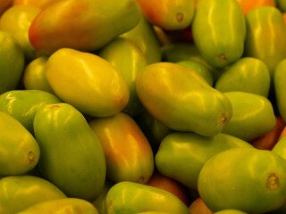 Closeup shot of a pile of yellow bell tomatoes found in the marketplace