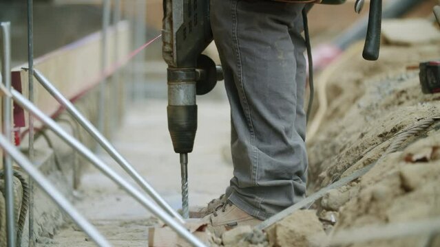 Beautiful view of an hardworking constructor using a drill for  making a building