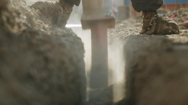 Closeup of the construction sand and soil and a builder digging it with a special shovel