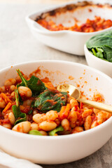 Healthy breakfasts and lunches, stewed white beans with carrots, onions and tomatoes with spinach leaves, a bowl of beans and spinach