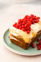 Rich sweet pie with fresh fruits, decorated with red currants and raspberries, in a plate on a pink background