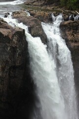 Vertical shot of a big waterfall coming down the rocky cliffs during the daytime