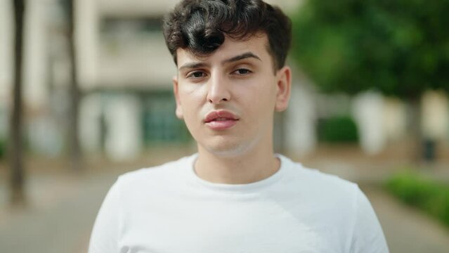 Non binary man standing with serious expression at park