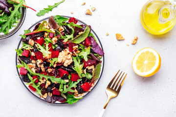 Beet and herbs healthy salad with prunes, arugula, chard and walnuts, gray table. Fresh useful vegan dish for healthy eating
