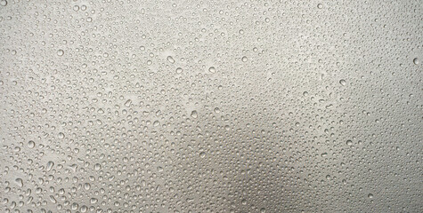 Photo of raindrops on a chrome-plated iron background. The texture of round dew drops on the silver banner shape. Evaporation of moisture on the iron.