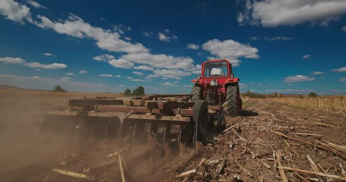 Tractor working on a field and harrow the ground, spring tillage. Farmer in tractor preparing land with seedbed cultivator