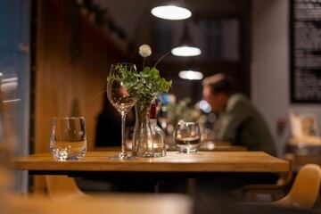 Close-up shot of glasses on a restaurant table with a background of a couple in a blur