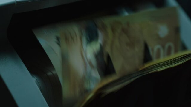 Up-close shot of a cashier counting lots of Canadian dollars in cash