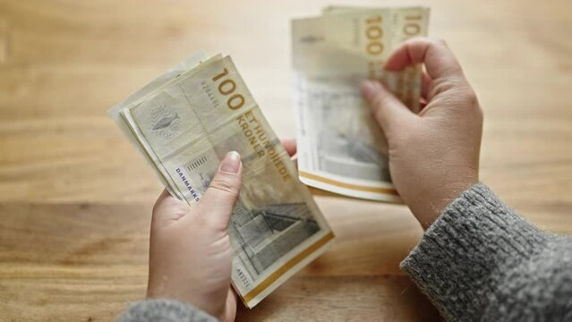 Hands of woman counting hundred denmark krone banknotes at room