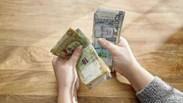 Hands of woman counting peruvian soles banknotes at room