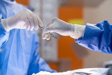 Team of surgery doctor in Operating Room hold hands scalpel surgical blade give to Surgeons During...