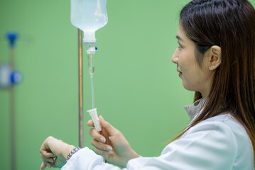 Woman doctor monitor Adjust the drip rate feed of saline dripping intravenous infusion to patient...