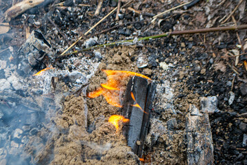 A fire burns in a campfire with a red fire in the background. High quality photo