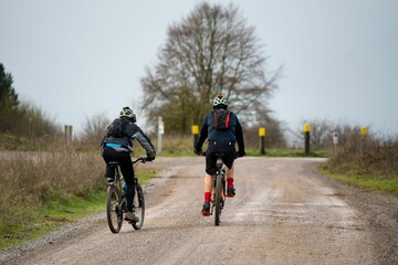 Naklejka premium Rear view of a pair of cyclists riding their off-road bikes along a stone track
