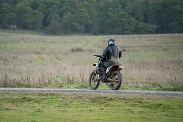 Obraz na płótnie Canvas Rear view of a motor cyclist (biker) riding their off-road motorbike along a stone track