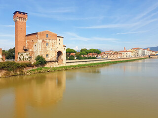 Fototapeta na wymiar View of the brown tower Guelph and the street of Pisa from the bridge of the Arno river.