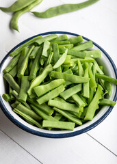 Fresh green beans in a bowl on a white wooden table. Bowl of green beans on wooden background. 