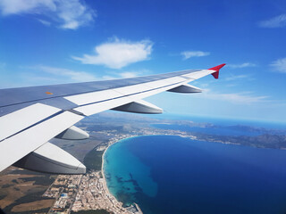 View from airplane window flying above the blue ocean.